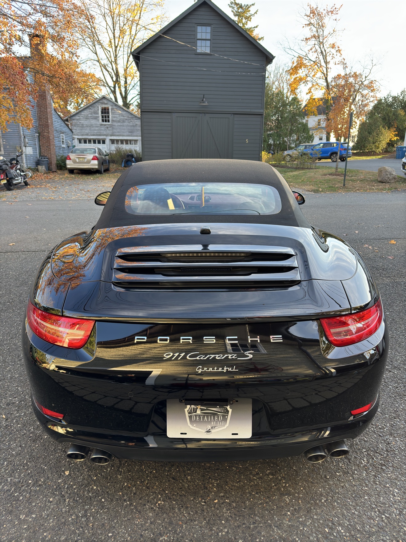 Rear view of a black Porsche 911 Carrera S with Grateful script badge and Detailed by Yael plate frame