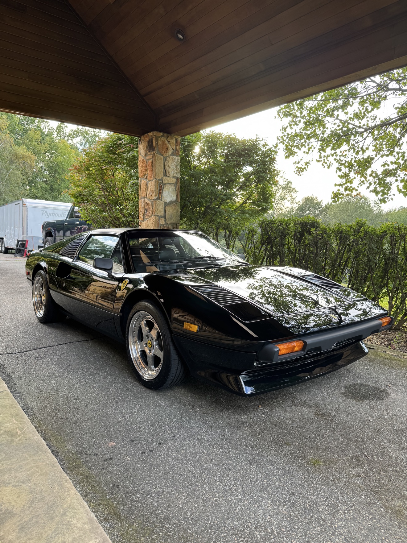 Black Ferrari 308 GTS front three-quarter view under a porte-cochere after detailing