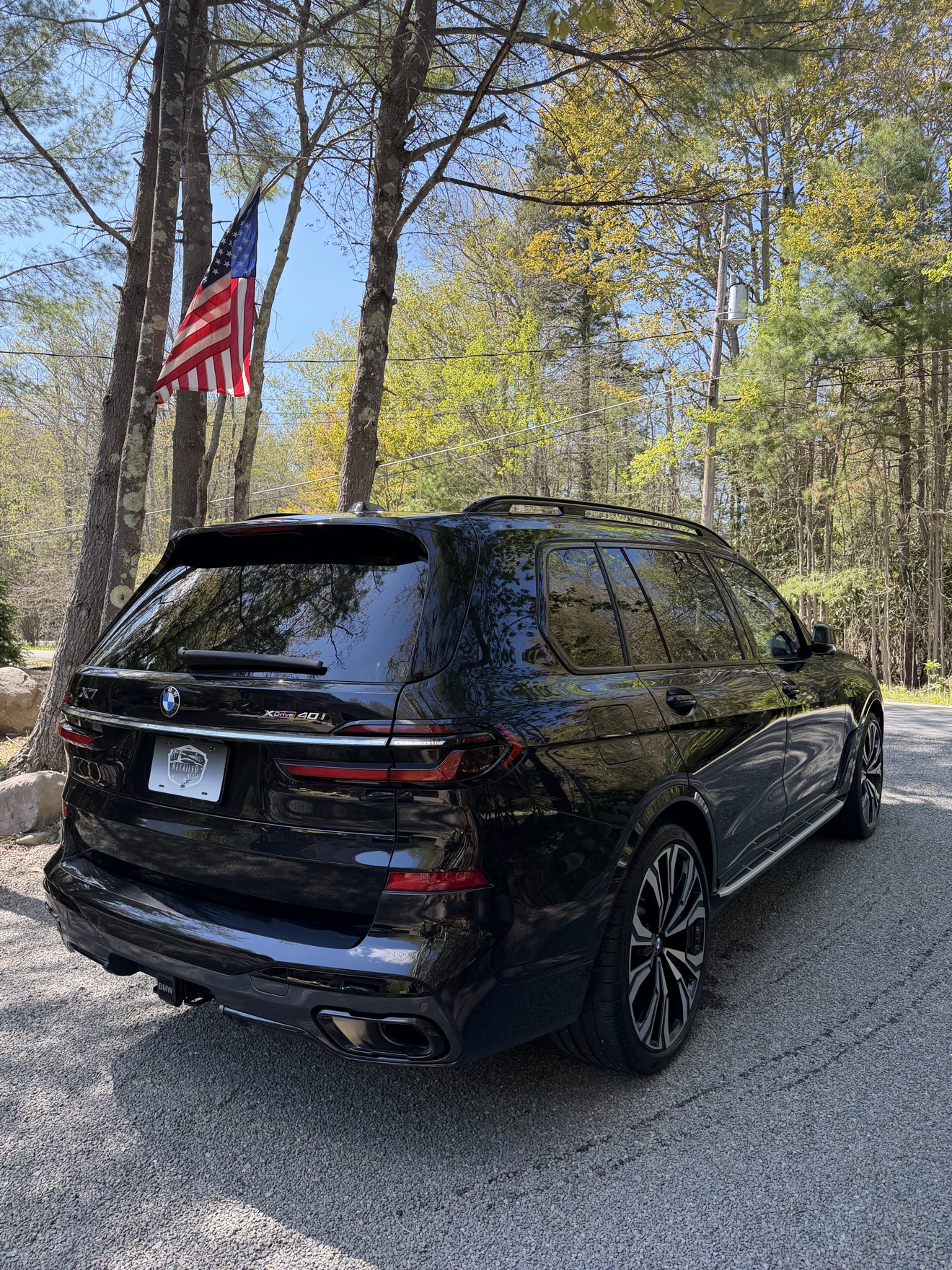 Black BMW X7 rear three-quarter view with X7 xDrive40i badge and Detailed by Yael plate frame