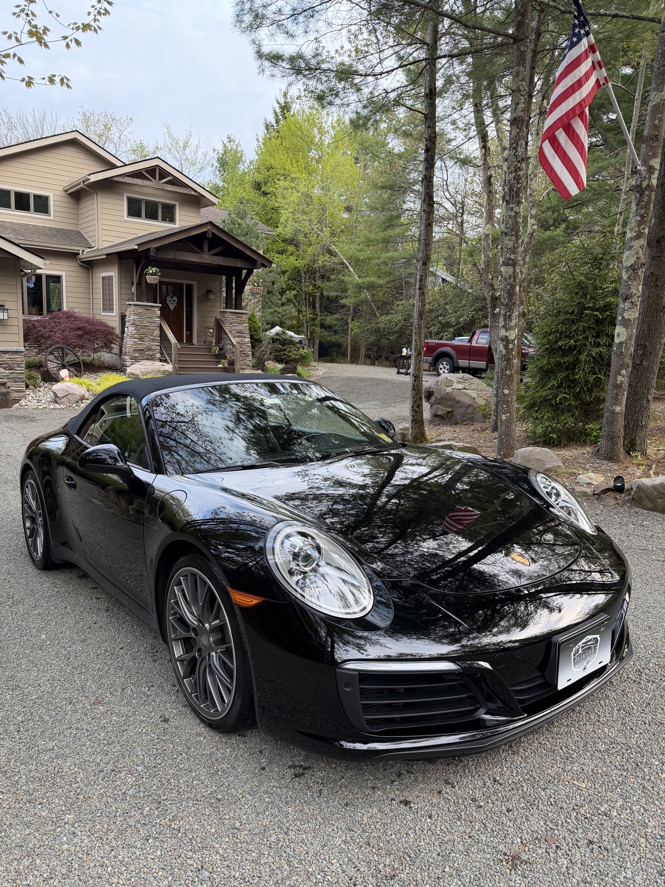 Black Porsche 911 Carrera Cabriolet front three-quarter view in a driveway after detailing