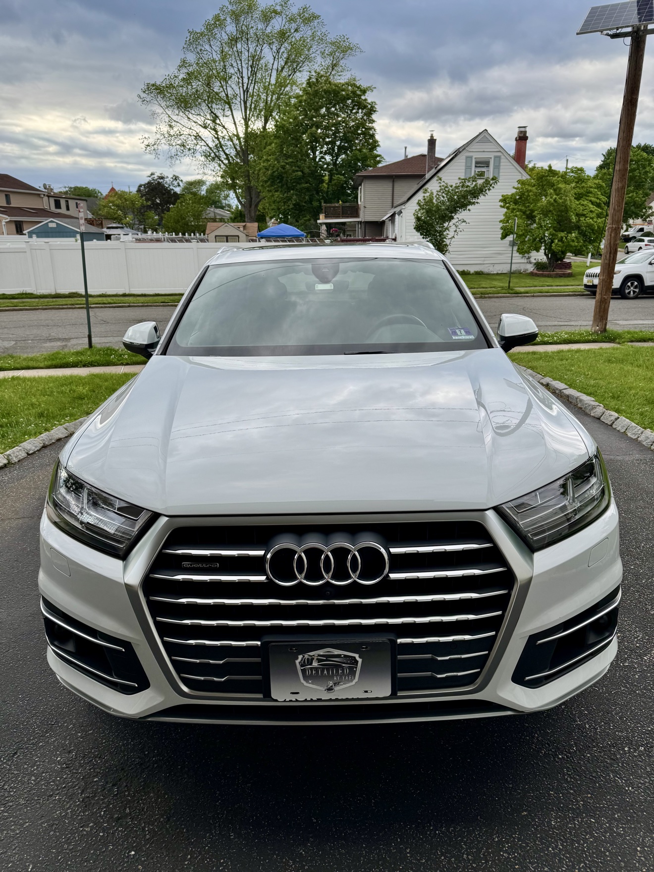 Front view of a white Audi Q7 with Detailed by Yael plate frame