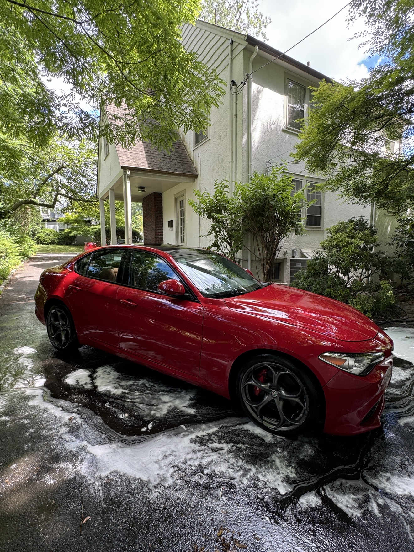 Red Alfa Romeo Giulia Q4 side profile in a driveway after detailing