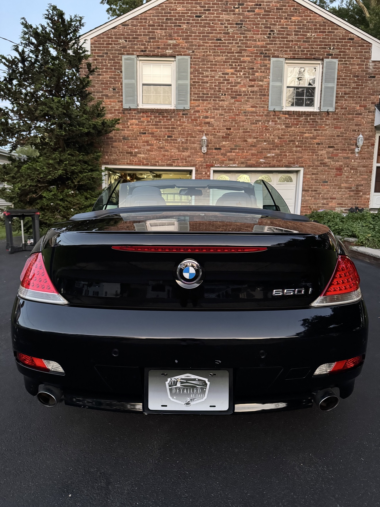 Rear view of a black BMW 650i convertible with 650i badge and Detailed by Yael plate frame