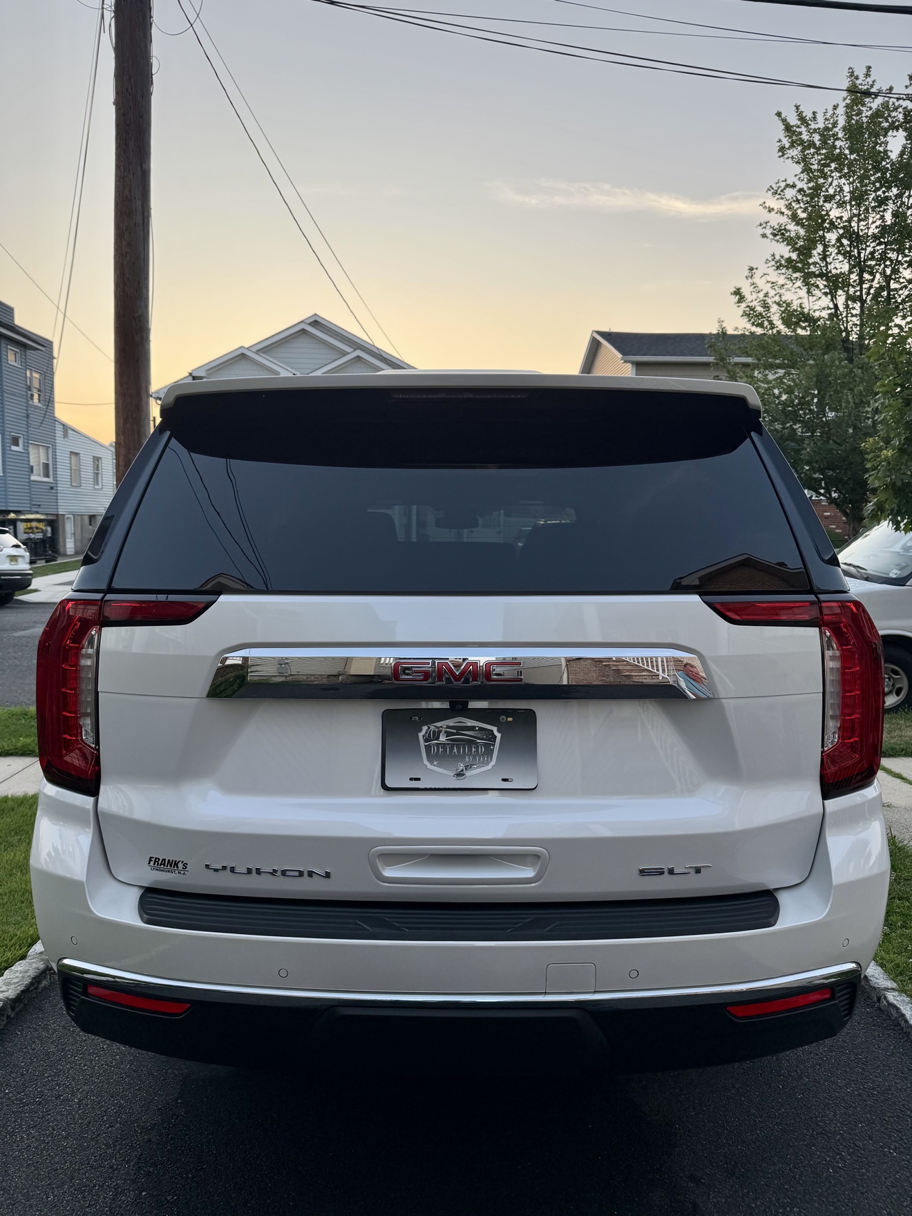 Rear view of a white GMC Yukon SLT with YUKON and SLT badges and Detailed by Yael plate frame