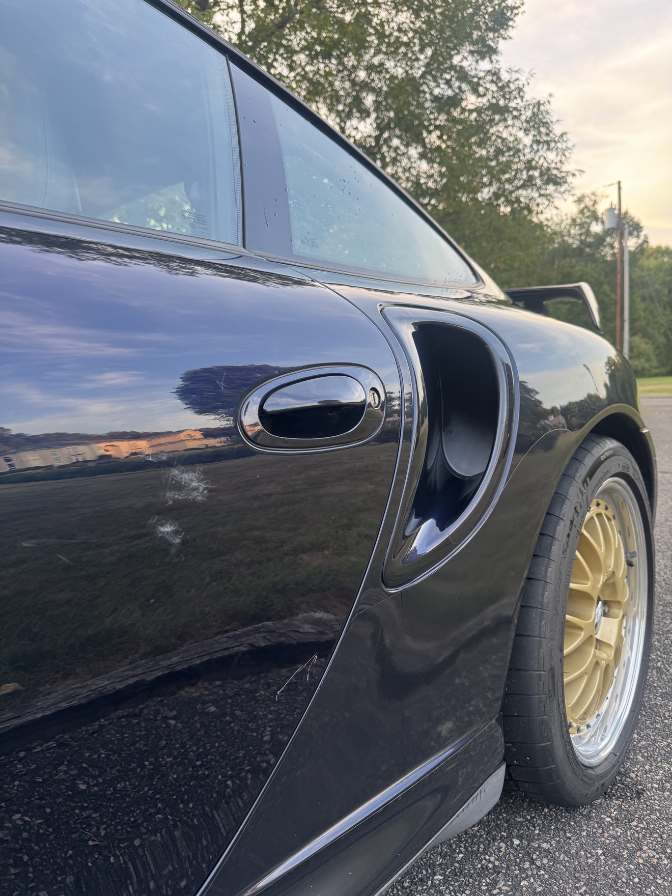 Close-up of the side intake and gold BBS wheel on a black Porsche 911 Turbo