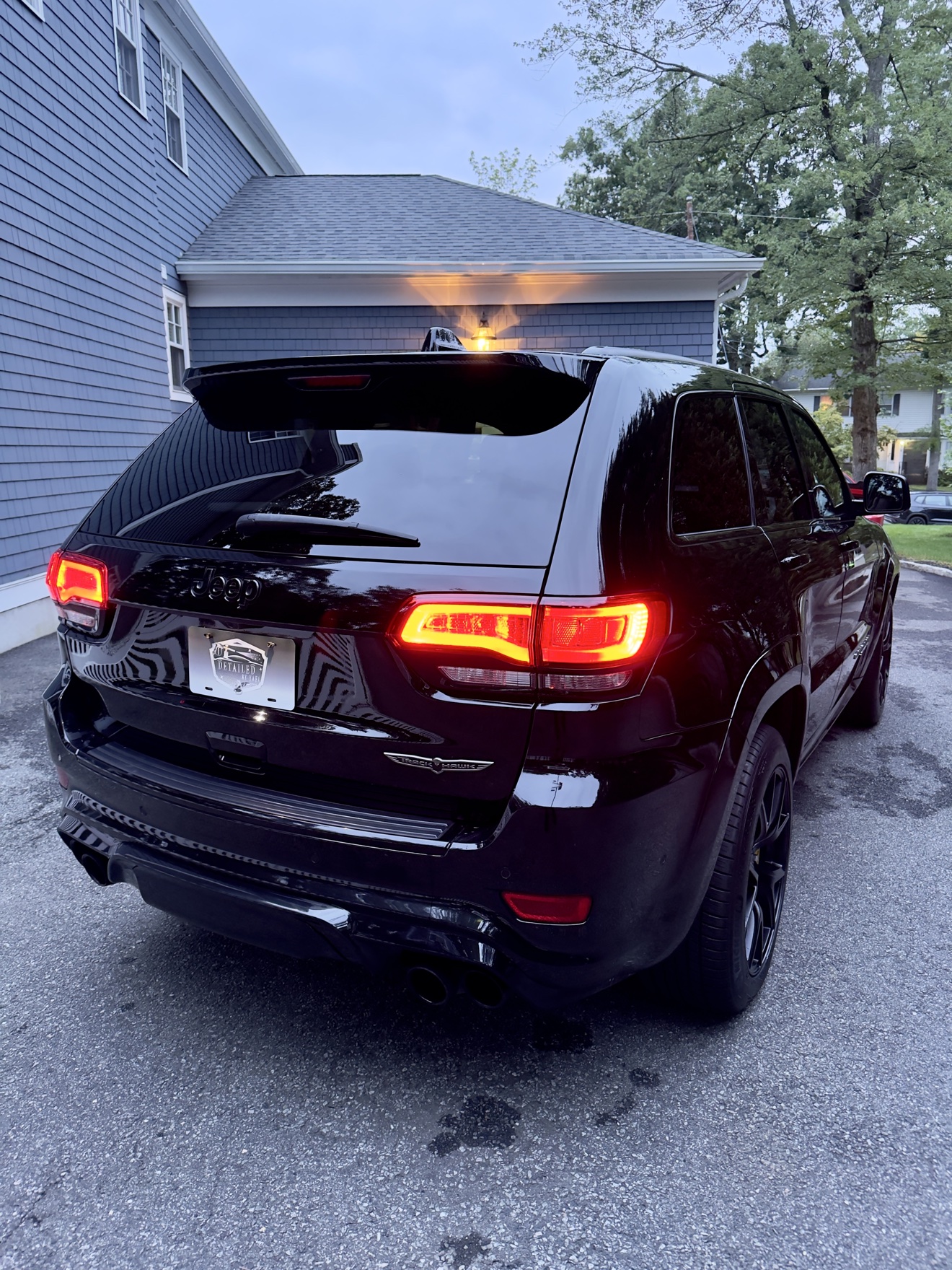 Rear three-quarter view of a black Jeep Grand Cherokee Trackhawk with Detailed by Yael plate frame